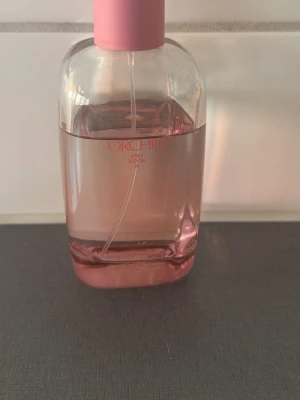 Zara Orchid Bloom parfym rosa - Fräsch parfym från Zara i doften Orchid Bloom. Flaskan är genomskinlig med rosa ton och har ett rosa lock. Modern och stilren design som passar perfekt på sminkbordet. Glasflaska med enkel sprayfunktion.