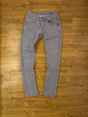 Grå slim fit jeans från Dondup -  HALLÖ! Jag erbjuder dessa eleganta Dondup RITCHE-jeans till försäljning. De har enastående kvalitet och enastående fades. RITCHE-modellen liknar George i passform.  Jeansen är i utmärkt skick och har en mycket attraktiv design. Mått: Längd: 102 cm, Midja: 35 cm, Storlek: W30.  Kontakta mig gärna vid eventuella frågor.