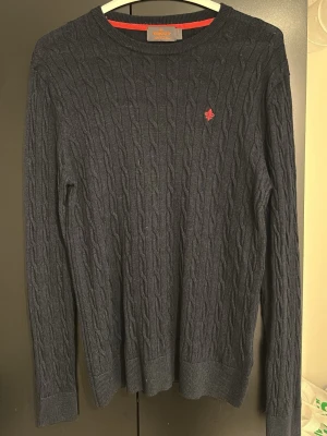 Mörkblå kabelstickad tröja Morris - Mörkblå kabelstickad tröja från Morris. Det står att tröjan är i storlek L men jag skulle säga att den snarare passar som storlek M då jag som är 180cm 72kg kan ha på mig den. Den är använd 2 gånger