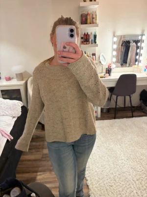 Beige stickad tröja från ONLY - Mysig beige stickad tröja från ONLY med rund halsringning och diskret hålmönster. Tröjan har en avslappnad passform och långa ärmar, perfekt för lager på lager under kyliga dagar. Passar till både jeans och kjol för en enkel vardagslook. 