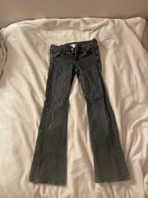 Svart/mörkgrå bootcut jeans - Snygga mörkgrå bootcut jeans med låg midja. Dem är en aning slitn och skrynkliga som ni kan se på bilderna.