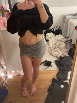 Grå tight kortkjol i bomull - Säljer en grå tight kortkjol i mjukt bomullsmaterial. Kjolen har en enkel och stilren design med lätt drapering framtill. Perfekt för dig som gillar en basic look med en twist.