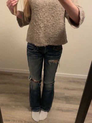 Beige stickad tröja med struktur - Mysig beige stickad tröja med lös passform och trekvartsärmar. Tröjan har en grovstickad struktur och är något kortare i modellen. Perfekt att matcha med jeans för en avslappnad look.