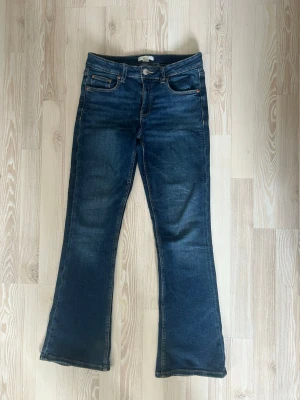 Mörkblå bootcut jeans - Snygga mörkblå bootcut jeans med klassisk femficksdesign och orangea sömmar. Jeansen har en lätt utsvängd passform nertill och är tillverkade i denim med stretch för extra komfort. Storlek 152 men passar mig som har xs/s
