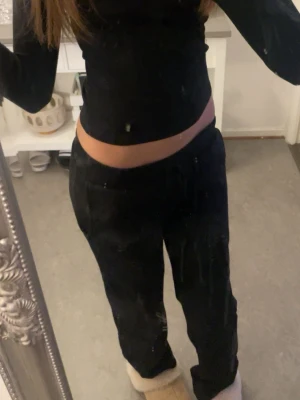 Svarta mjukisbyxor med dragsko - Säljer ett par svarta mjukisbyxor med avslappnad passform och dragsko i midjan. Byxorna har raka ben och resår i midjan för extra komfort. Perfekta för chill dagar hemma eller när du vill vara bekväm. Materialet ser ut att vara mjukt och skönt.