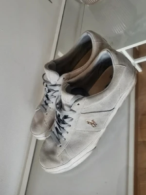 Gråa sneakers från Ralph Lauren - Snygga grå sneakers från Ralph Lauren i mockaliknande material med klassisk låg profil. Perfekta för en clean och stilren look.