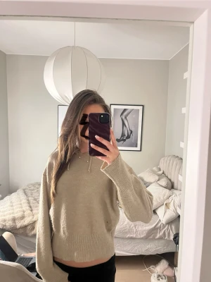Beige stickad hoodie med huva - Mysig beige stickad hoodie med huva och dragsko. Tröjan har en avslappnad passform, ribbade muddar och är lite croppad i modellen. Perfekt för chill dagar och enkel att matcha med jeans eller mjukisbyxor.