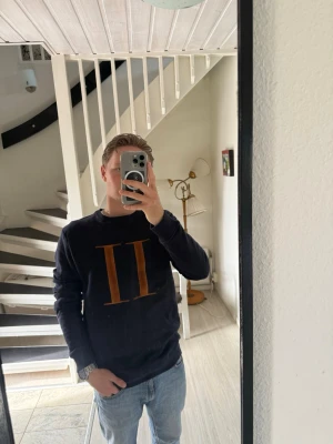 Svart sweatshirt från Les Deux - Säljer en svart sweatshirt från Les Deux med deras ikoniska bruna romerska siffror II på bröstet. Tröjan har rund halsringning och långa ärmar. Perfekt för en avslappnad och stilren look.