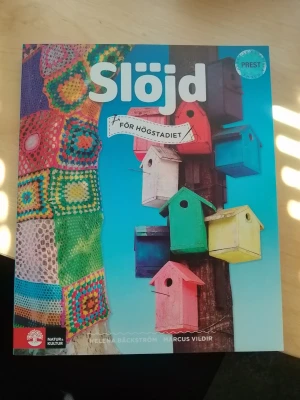 Slöjd för högstadiet kursbok  - Slöjd för högstadiet är en färgglad kursbok skriven av Helena Bäckström och Marcus Vildir. Omslaget har virkade mönster och fågelholkar i olika färger mot blå bakgrund. Boken täcker trä, textil och metallslöjd och är tryckt i mjukt papper. Slöjd för högstadietUpplaga 1 av Helena Bäckström, Marcus Vildir  Upplaga: 1a upplagan Utgiven: 2025 ISBN: 9789127468214 Sidor: 192 st Förlag: Natur & Kultur Läromedel och Akademi Format: Häftad Språk: Svenska