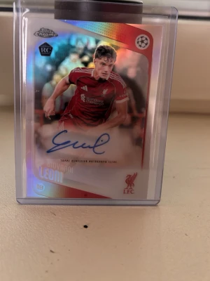 Autografkort äkta Giovanni Leoni Liverpool - Samlarkort med autograf av Giovanni Leoni från Liverpool FC, UEFA Champions League 2025/26. Kortet är i plastfodral och har röd, vit och svart design med klubbens logga. Perfekt för fotbollsfans och samlare.