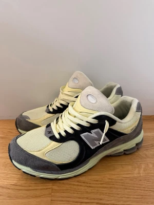 New Balance 2002R gul/svart/grå - Snygga New Balance 2002R sneakers i en mix av gult, svart och grått. Ovandelen är i mesh och mocka med klassisk N-logga på sidan. Skorna har en chunky sula och retrovibbar, perfekta för dig som gillar streetwear och sportig stil. Använt 1 gång men dom är för små och kunde inte lämna tillbaka dom. 