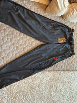 Grå meshbyxor från GASP - Snygga grå mjukisbyxor från GASP i meshmaterial med svart tryck längs benet och elastisk midja. Perfekta för gymmet eller chill hemma. Byxorna har en sportig look och är lätta och luftiga. helt nya fick i present lapp o allt kvar!
