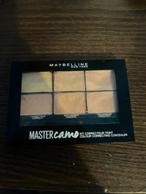 Maybelline Master Camo Concealer Kit - Maybelline Master Camo Concealer Kit i färgen Medium. Paletten innehåller sex krämiga nyanser för att korrigera, täcka och highlighta. Perfekt för att jämna ut hudtonen och dölja ojämnheter. Kompakt svart plastförpackning med genomskinligt lock.