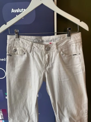 Vita jeans från Esprit - Säljer ett par vita jeans från Esprit med snygga silverknappar och ditaljer. Byxorna sitter låhmidjat men säljer på grund av för lite användning 