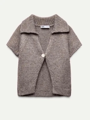 Grå stickad kofta från Zara - Kortärmad grå stickad kofta från Zara med bred krage och en knapp framtill. Koftan har en avslappnad passform och ribbade detaljer vid ärmslut och nederkant. Perfekt för lager på lager och en chill look.