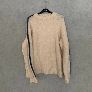Paloma Wool Knit - .Säljer en stickad tröja från Paloma Wool i varm, krämig ton med blå kontrastdetalj längs ärmen. Avslappnad silhuett med tydlig designkänsla – exakt den där konstnärliga, effortless vibben märket är känt för. 🔹 Märke: Paloma Wool 🔹 Färg: Off-white / kräm med blå rand 🔹 Material: Ullblandning (mjuk & lätt fluffig) 🔹 Passform: Avslappnad / rak (PASSAR S/M) 🔹 Detaljer: Kontraststripe på ärm, ribbad mudd & hals 🔹 Skick: Mycket bra Funkar lika bra till jeans som dressade byxor