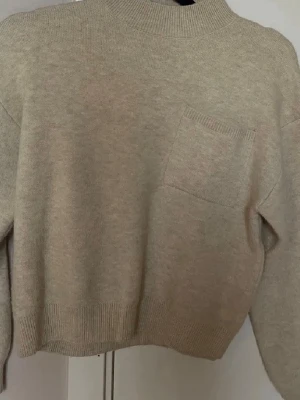 Beige stickad tröja från Zara - Beige stickad tröja från Zara med rund halsringning och ribbade muddar. Tröjan har en liten bröstficka och är i en mjuk, skön kvalitet som passar perfekt till kyligare dagar. Enkel och stilren design som funkar till det mesta. (Jag noppar av den innan jag skickar!) 