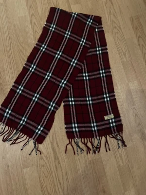 Rutig vinröd halsduk från Burberry - Varm burberry halsduk  100%äkta burberry  Färg- Vinröd färg med en vit nyans  Storlek- No size   Pris går att diskuteras vid snabb affär!      Skickar inom 24h📦🚚  Har du någon fråga är det bara att fråga på! 