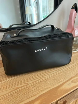 ESSNCE NECESSÄR LARGE - Snygg svart necessär från ESSNCE i slät konstläder med dragkedja och praktiskt handtag. Insidan har flera fack och elastiska band för att hålla ordning på dina grejer. Aldrig använd!