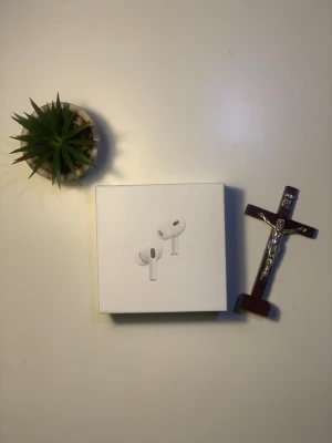 Apple AirPods Pro (Gen 2) trådlösa hörlurar - Säljer ett par Apple AirPods Pro i originalförpackning. De är vita, har en stilren och kompakt design och levereras i en snygg vit box. Perfekta för dig som vill ha grymt ljud, brusreducering och smidig anslutning till din iPhone eller andra Apple-enheter.