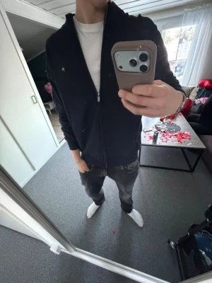 Mörkblå ziptröja från Peak Performance - Snygg mörkblå ziptröja från Peak Performance med liten logga på bröstet. Tröjan har hög krage, dragkedja hela vägen och ribbade muddar. Perfekt att slänga på sig över en t-shirt. Materialet är mjukt och stretchigt för skön passform.