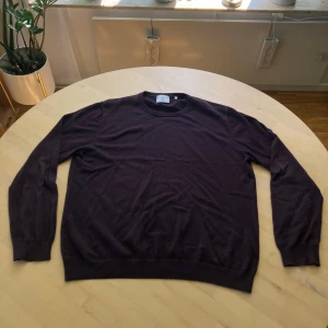 Mörklila stickad tröja från Bläck XL - Säljer en stilren mörklila stickad tröja från Bläck i storlek XL i gott skick. Tröjan har rund halsringning, långa ärmar och ribbade muddar vid ärmslut och nederkant. Perfekt för dig som gillar en enkel men snygg look.