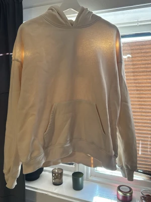 Beige hoodie med LIMITED EDITION-tryck - Säljer en beige hoodie med stor ficka framtill och huva. På ryggen står det 'LIMITED EDITION' i svart text. Hoodien har en relaxed passform och är perfekt för dig som gillar streetwear vibes.