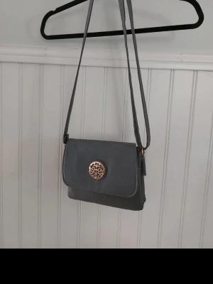 Axelväska  - Handväska månag olika fack ca. 8 stycke och axelbandet går att ändra länden  Dock är den lite trasig i dragkedja bandet ska finns ett avslut på men ramlat av.Jag stoppar in den i själva väskan så syns det ej! Syns på bilderna  Djur finns I hemmet  Rökfritt