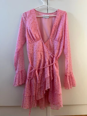 Prickig klänning - Rosa/röd prickig klänning från ASOS. Omlott med knytning fram. Volangärmar. 