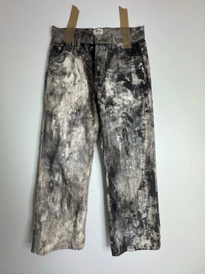 Gråsvarta wide leg jeans från MIJKO - Unika wide leg jeans från MIJKO med coolt gråsvart mönster i tvättad look. Jeansen har raka ben, klassisk femficksdesign och knappgylf. Perfekta för dig som vill sticka ut med en kreativ och edgy stil.