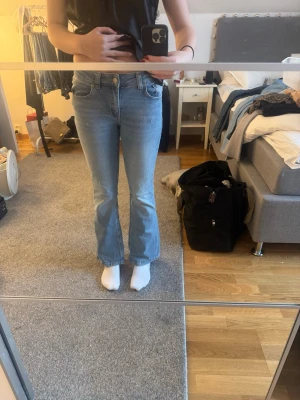 Bootcut jeans från lager157 i ljusblå denim - Säljer ett par ljusblå bootcut jeans från lager157 med låg midja. Klassisk femficksmodell och slitstarkt denimtyg. Perfekta för dig som gillar retrovibbar och en avslappnad look. Stängs med knapp och dragkedja framtill.