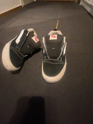 Svarta Vans Old Skool sneakers - Klassiska Vans Old Skool sneakers i svart canvas och mocka med vit sula och vit sidoremsa. Skorna har lågt skaft, vita sömmar och Vans-logga på plösen och hälen. Perfekta för en avslappnad streetstil.