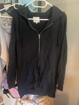 Svart hoodie från NEU - Säljer en svart hoodie från NEU i storlek M. Den har en dragkedja framtill och en bekväm huva med snörning. Perfekt för en avslappnad stil.