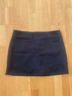 Kjol - Snygg svart kortkjol med två dekorativa fickor framtill från Cider i Strl S 🌸 Kjolen har en diskret dragkedja bak och är perfekt för en clean och stilren look. Materialet känns mjukt och har en lätt stretch. 