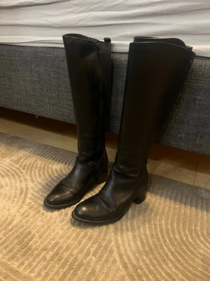 Svarta knähöga läderstövlar - Snygga svarta knähöga stövlar i äkta läder med låg klack och dragkedja på insidan. Klassisk och stilren design som passar till många outfits. Perfekta för dig som vill ha en tidlös look med edge. Dem är ifrån Dasia och kostar ca 2000 ute 