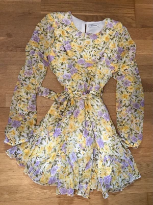 Klänning - En blommig klänning med snöre runt midjan som är man knyter på sidan. Storlek M