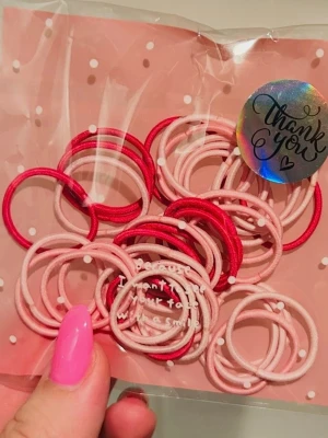 Rosa hårsnoddar - Säljer ett set med 40 elastiska hårsnoddar i rosa nyanser. Perfekta för att fixa olika frisyrer och hålla håret på plats. Kommer i en söt förpackning med prickigt mönster. Materialet är mjukt och skonsamt mot håret.