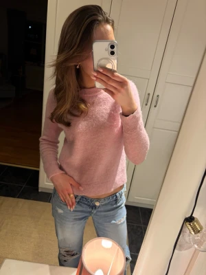 Ljusrosa stickad tröja - Mysig ljusrosa stickad tröja med rund halsringning och långa ärmar. Tröjan har en enkel, rak passform och ribbade muddar vid ärmslut och nederkant. Perfekt för att hålla värmen under kyliga dagar och passar till både jeans och kjol. Jätte fin tröja till våren! Nypris 600 kr säljer för 250 kr men pris kan diskuteras vid snabb affär!💕😚