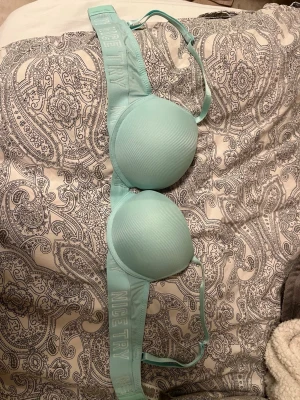 Ljusblå bygel-bh från Nice Try - Snygg ljusblå bh med vadderade kupor och bygel för extra stöd. Axelbanden är justerbara och bandet har texten 'NICE TRY' broderat. Materialet känns mjukt och stretchigt, perfekt för en bekväm känsla hela dagen.