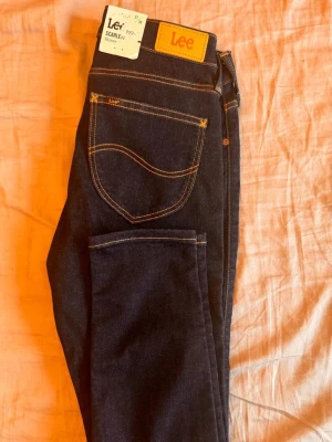Mörkblå Lee Scarlett jeans - Snygga mörkblå Lee Scarlett jeans med klassisk femficksdesign och kontrastsömmar. Jeansen har en rak passform och är tillverkade i slitstark denim. Perfekta för dig som gillar tidlös och enkel stil. Jag har köpt den helt  ny från Lee butiken. 