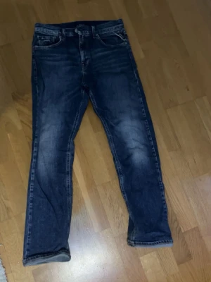 Mörkblå jeans från replay  - Säljer ett par mörkblå jeans från replay med klassisk femficksmodell och raka ben. Jeansen har snygga slitningar och kontrastsömmar samt replay-loggan på bakfickan. Perfekta till en avslappnad streetstil.                    Den ända nackdelen med jeansen är att det finns hål i fickorna, men det går lätt att sy ihop.