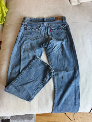 Levi's ljusblå flare jeans - Säljer ett par klassiska ljusblå jeans från Levi's med raka ben och femficksmodell. Jeansen har tydliga sömmar, läderpatch bak i midjan och den ikoniska röda Levi's-lappen på bakfickan. Perfekta för en avslappnad och trendig look.