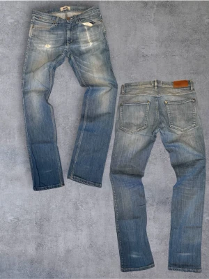 Sjukt feta Acne jeans i straight fit - Säljer ett par ljusblå jeans från Acne med raka ben och klassisk femficksmodell. Jeansen har slitningar och diskreta detaljer framtill för en avslappnad look. Tillverkade i bomull med snygg tvätt och läderpatch bak i midjan.