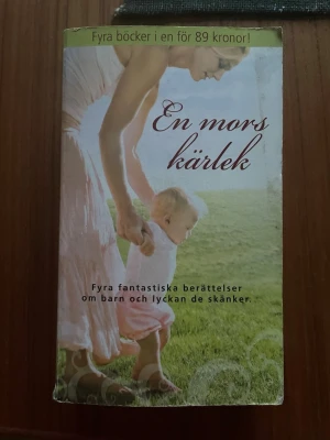 En mors kärlek - Fyra berättelser - En samlingsbok med fyra gripande romaner om mammor, barn och kärlek. Innehåller berättelser av Cathy Williams, Lucy Gordon, Rebecca Winters och Susan Fox. Omslaget är grönt och vitt med ett foto av en mamma och ett barn på en gräsmatta. Utgiven av Harlequin.