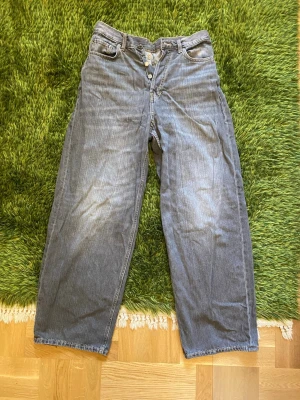 Weekday Gråa Astro Loose baggy jeans - Säljer ett par gråa jeans med rak/baggy passform och knappgylf. Jeansen har klassiska fem fickor och är tillverkade i denim med snygg grå wash. Perfekta för en avslappnad och trendig look.