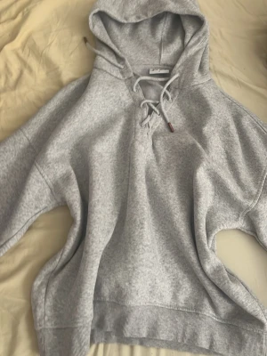 Ljusgrå stay hoodie med snörning  - Ljusgrå hoodie från stay med huva och snörning framtill. Tillverkad i mjukt sweatshirtmaterial och har ribbade muddar vid ärmslut och nederkant. Perfekt för en avslappnad och stilren look.