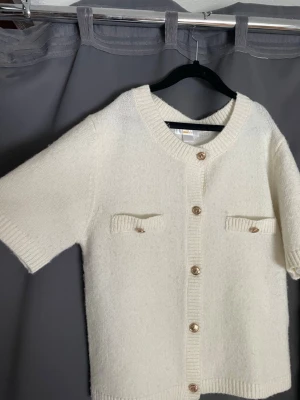 Vit stickad kofta med kort ärm -  vit stickad t shirt/ kofta med fickor framtill från Gina tricot Young i storleken 170. Använd men i väldigt bra skick och inga skavanker. Sänkt pris vid snabb affär.