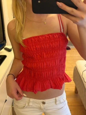 Röd linnetopp med volang - Säljer en röd croppad linnetopp som har en söt volangkant nedtill. Den är perfekt för varma dagar nu till sommaren och enkel att styla med jeans eller kjol🙌🏼❣️