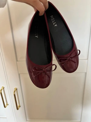 Vinröda ballerinaskor  - Snygga vinröda ballerinaskor från Nelly i glansigt material med rund tå och en söt rosett framtill. Köpte skorna på Vinted men använt dem någon enstaka gång, har en liten defekt på sidan av skon (kan såklart få bild på det om man vill och är intresserad) 💖