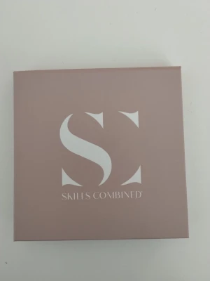 Skills Combined bronzer face palett - Bronzerpalett från Skills Combined med fyra nyanser i en rund dosa. Färgerna går i varma toner av brunt, beige och persikorosa. Kommer i en stilren, matt rosa ask med spegel i locket. Perfekt för att skapa en fräsch och solkysst look.